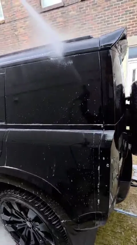 Rinsing a black Land Rover Defender during a valet