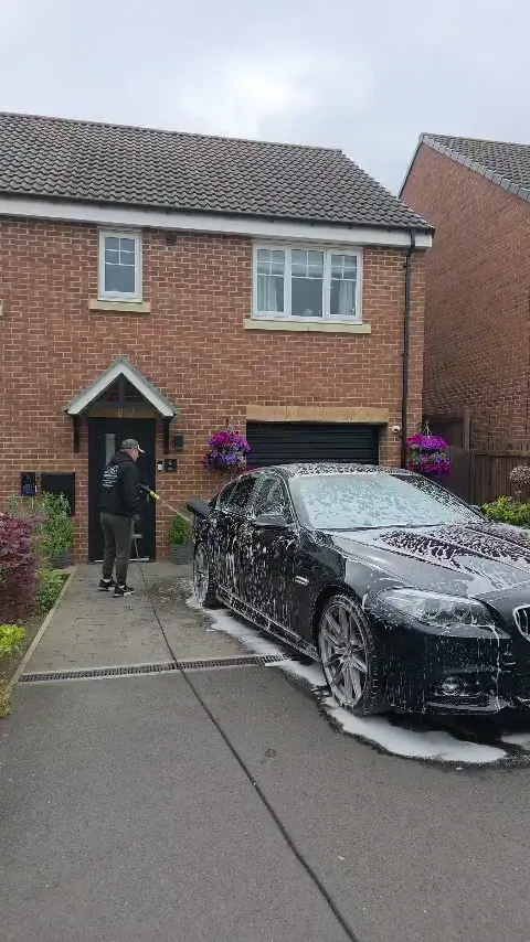 Snow foam wash on a black BMW outside a property