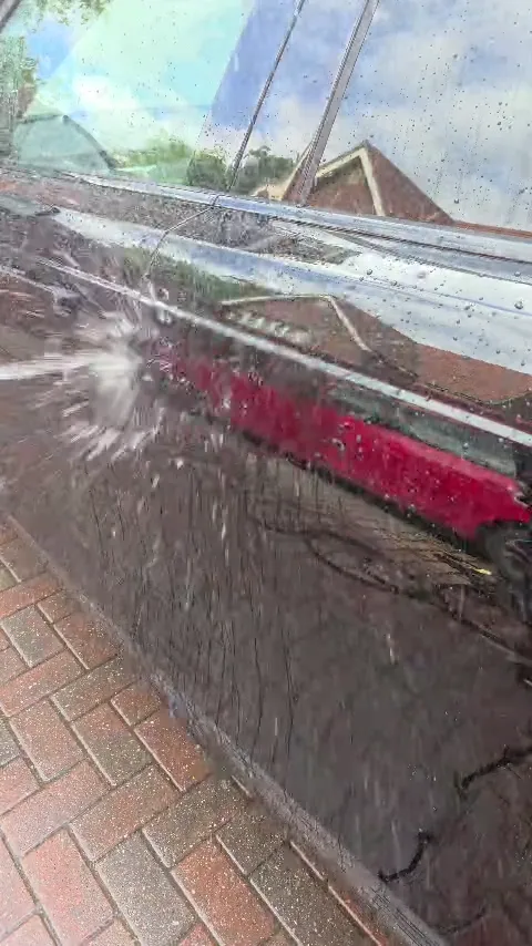 Pressure rinsing a red car's paintwork